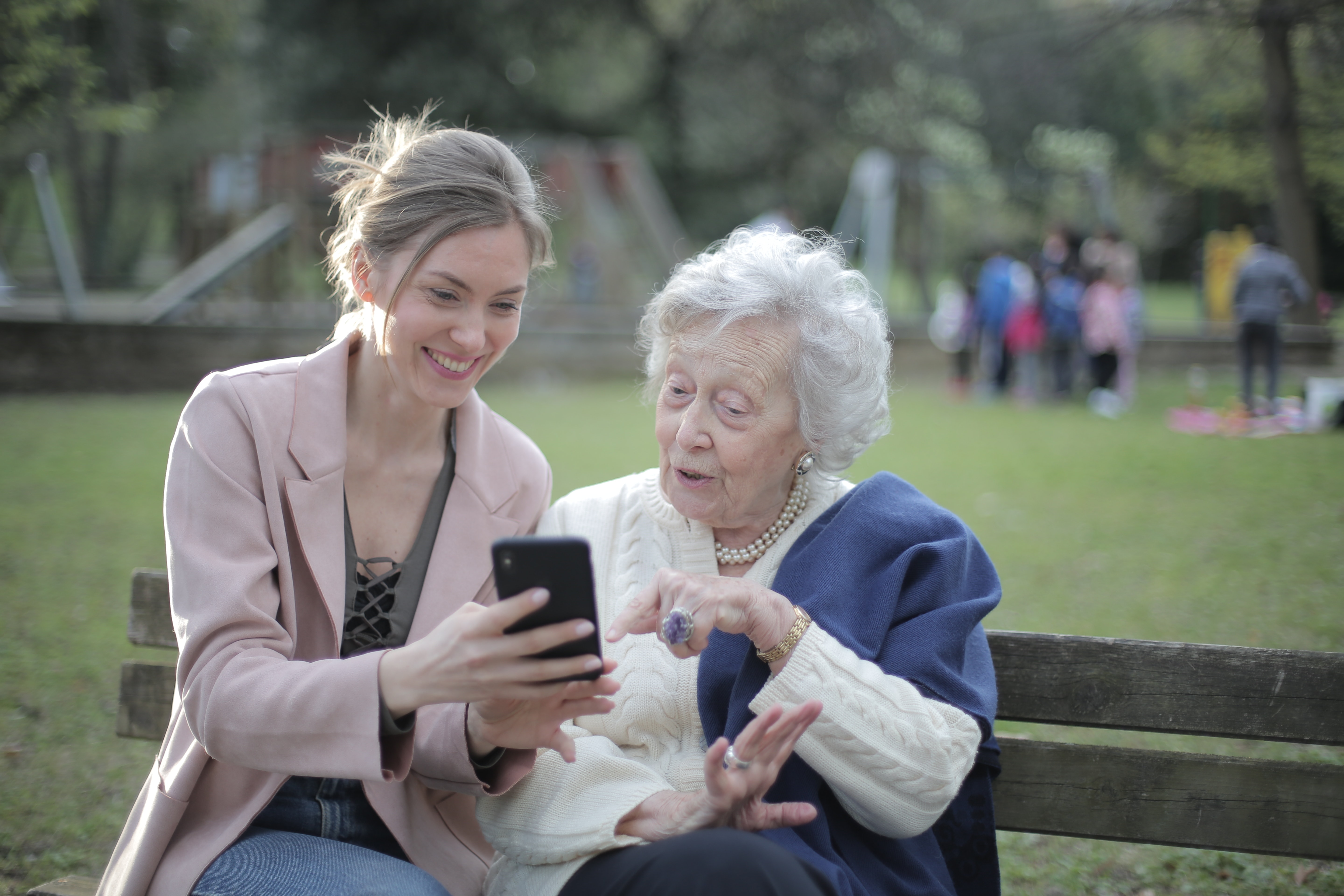 Two women enjoying senior activities for August on a park bench.
